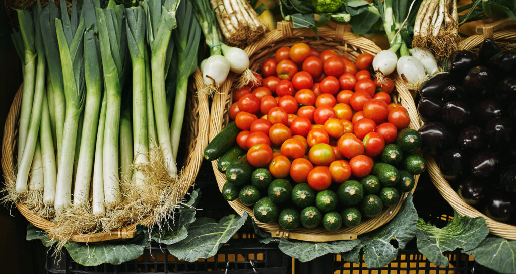 Fresh harvest in basket beautifully presented outside on market for sale: tomatoes, leek, zuccini, cabbage, garlic, etc