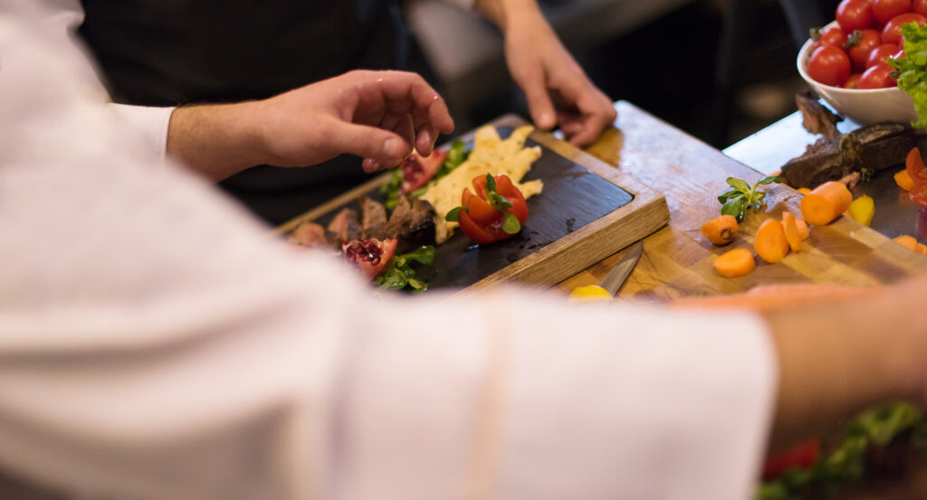 Professional team cooks and chefs preparing meal at busy hotel or restaurant  kitchen